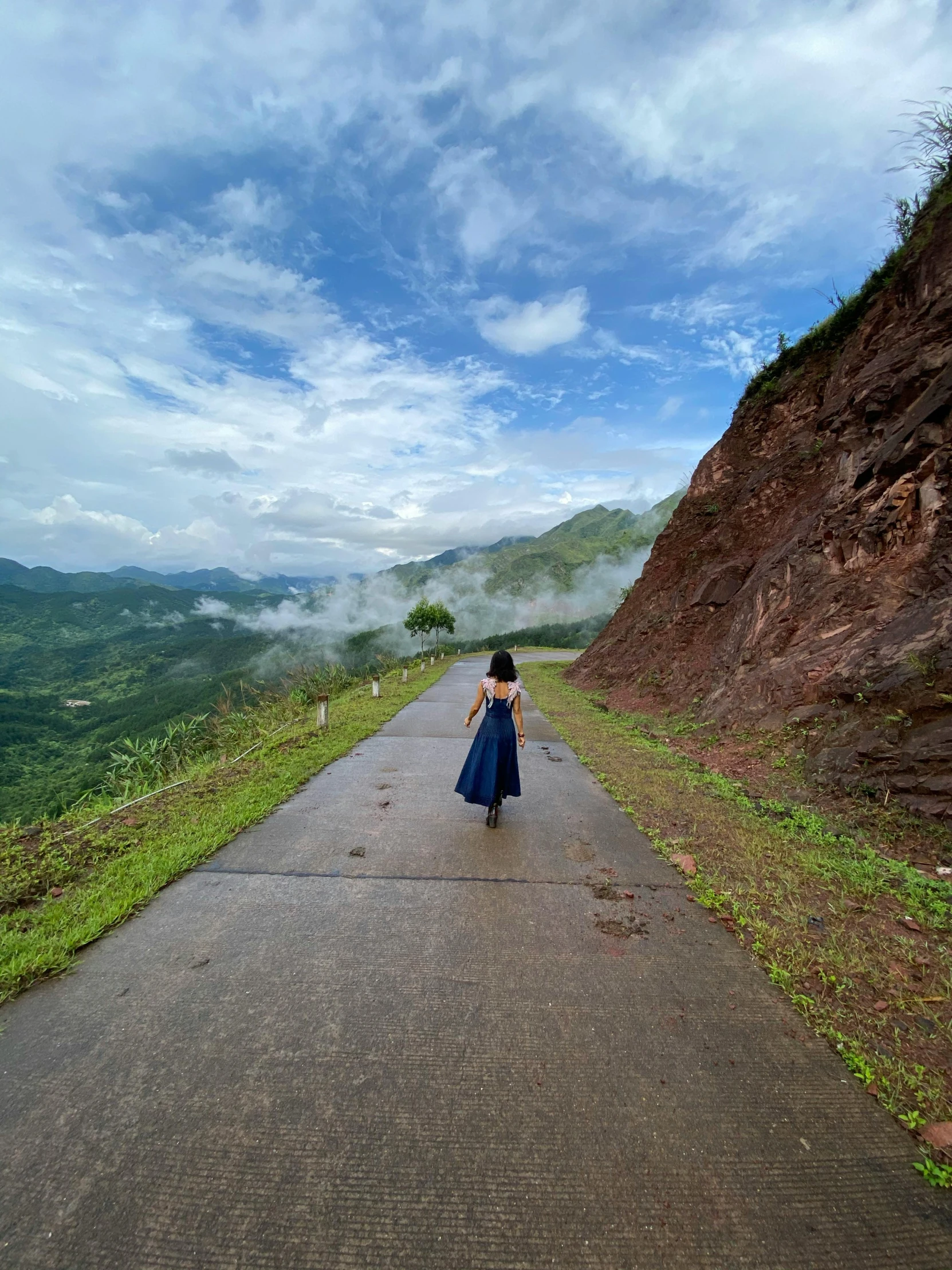 a woman in a blue dress walking down a road, inspired by Steve McCurry, happening, mountainous setting, in style of lam manh, slide show, overlooking