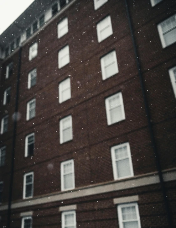 a tall brick building with lots of windows, inspired by Elsa Bleda, pexels contest winner, vancouver school, snow flurries, hotel room, grainy polaroid, background image