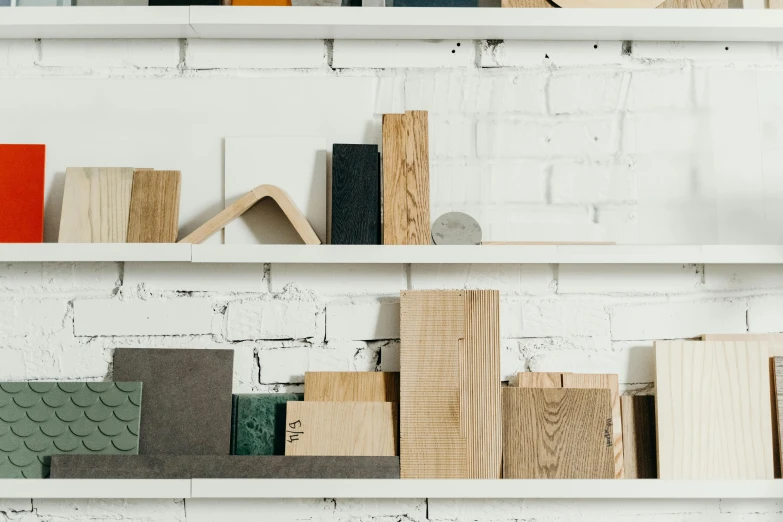 a shelf filled with books on top of a white brick wall, trending on unsplash, analytical art, wooden structures, holding a wood piece, in a workshop, product introduction photo