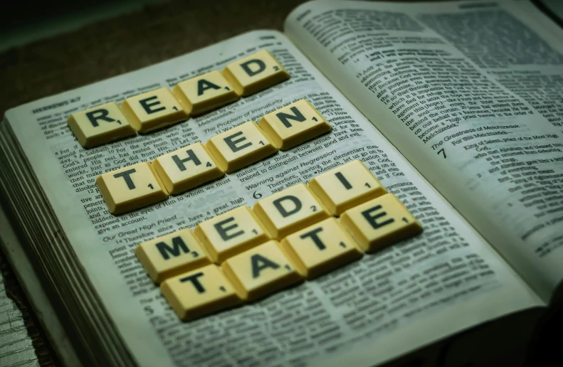 a close up of a book with scrabbles on it, a portrait, by Glennray Tutor, unsplash, hindu stages of meditation, sittin, metatron, ready to eat