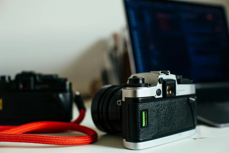 a camera sitting on top of a desk next to a laptop, a picture, posing for a picture, close-up photograph, zoomed in, medium - shot