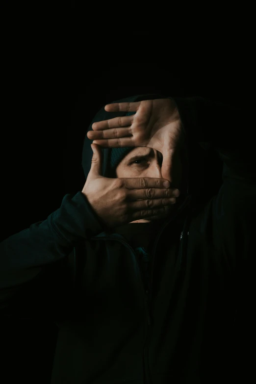 a man covering his face with his hands, an album cover, by Adam Marczyński, trending on pexels, realism, hooded figures, with a black background, face covers half of the frame, hands not visible