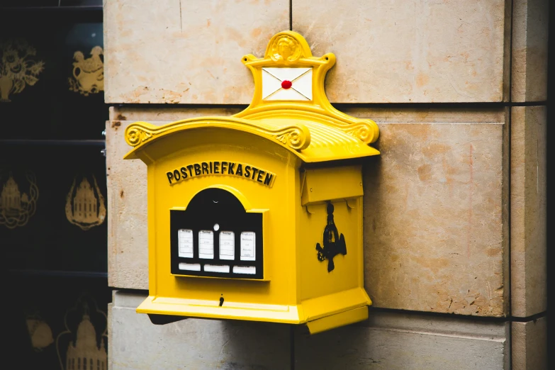 a yellow mail box sitting on the side of a building, inspired by Emil Bisttram, pexels contest winner, square, unsplash 4k, fanbox, multicolored