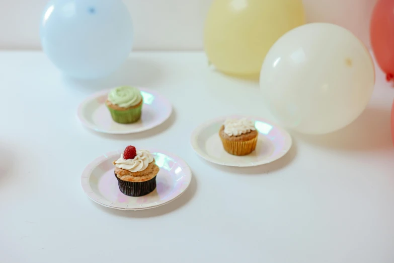 a table topped with plates of cupcakes and balloons, iridescent texture, 3 - piece, 3 5 mm colour, white pearlescent