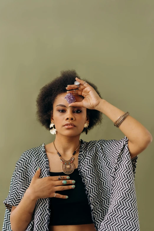 a close up of a person holding a cell phone, an album cover, inspired by Afewerk Tekle, nathalie emmanuel, jeweled ornament over forehead, solemn gesture, mid length portrait photograph