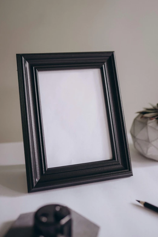 a black picture frame sitting on top of a white table, unsplash, photorealism, 2000s photo, product photo, traditional portrait, shaped picture