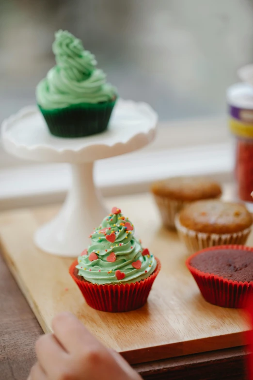 a wooden tray topped with cupcakes on top of a table, vibrant red and green colours, order, tree's, medium - shot