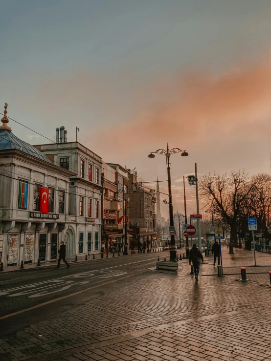 a group of people walking down a street next to tall buildings, by Julia Pishtar, pexels contest winner, art nouveau, mixture turkish and russian, at sunset in autumn, ground level view of soviet town, today\'s featured photograph 4k