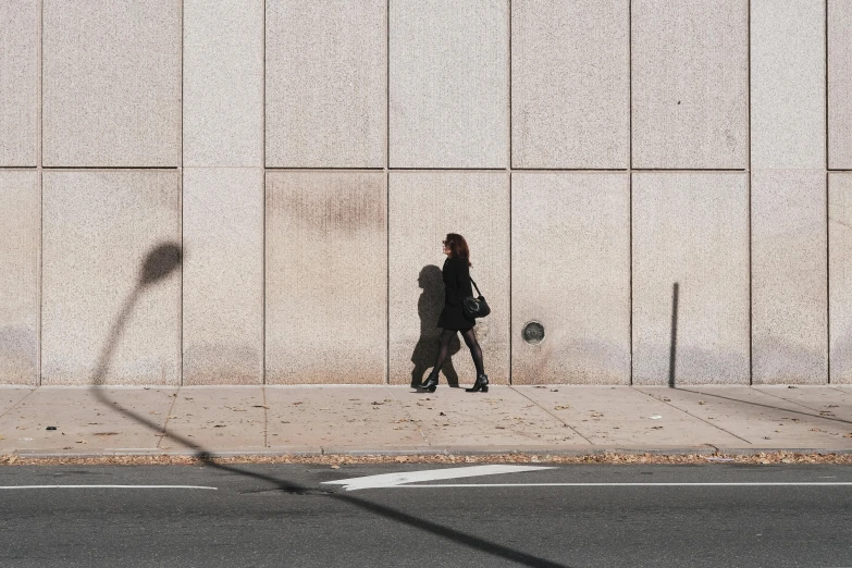 a couple of people that are walking down the street, a photo, unsplash contest winner, postminimalism, high shadow, ignant, brutalist city, 30 years old woman