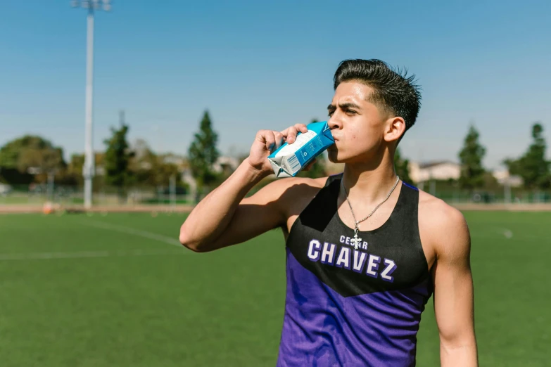 a man drinking water while standing on a soccer field, by Byron Galvez, violet tight tanktop, profile image