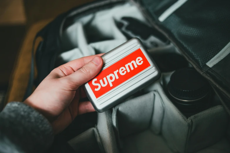 a person holding a box with a supreme sticker on it, trending on pexels, battery, metal lid, luggage, a 35mm photo