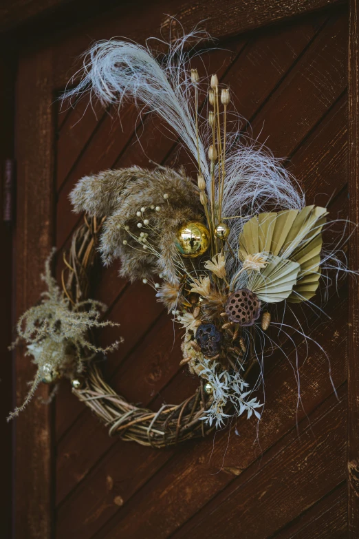 a close up of a wreath on a wooden door, a still life, unsplash, baroque, dry grass, avian-inspired, glittering and soft, half moon