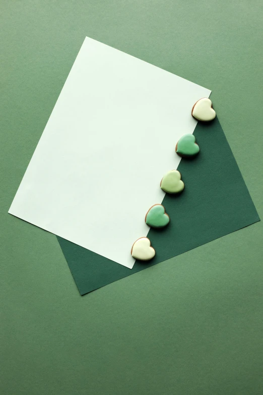 a piece of paper sitting on top of a green surface, cookies, hearts, understated aesthetic, on high-quality paper