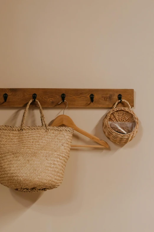 a basket hanging on a wall next to a coat rack, unsplash, cottagecore, bags, paul barson, people