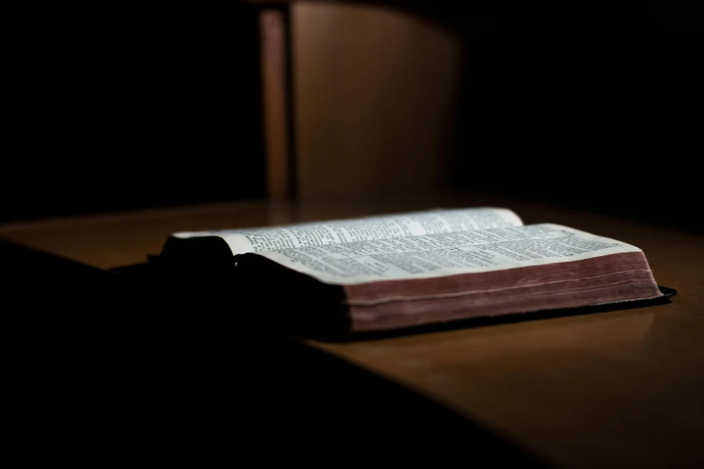 an open bible sitting on top of a wooden table, unsplash, unilalianism, glowing in the dark, instagram photo, thumbnail, angled shot