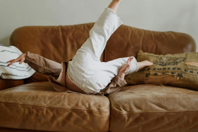 a person laying on top of a brown couch, inspired by Sarah Lucas, pexels contest winner, brown pants, excited, little kid, white pants