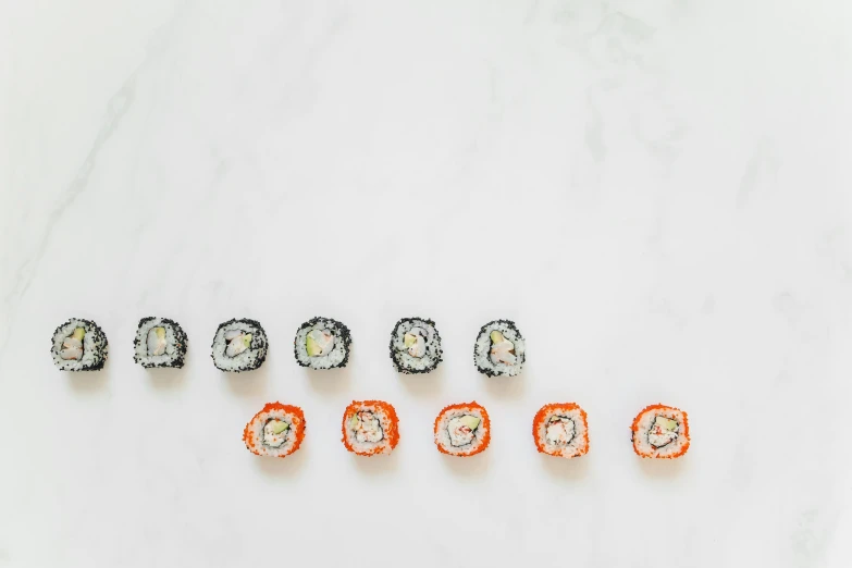 sushi rolls arranged in a row on a marble surface, an album cover, inspired by Maki Haku, unsplash, mingei, ffffound, white and orange, group of seven, sprinkles