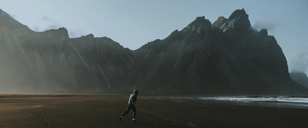a person walking on a beach with mountains in the background, a matte painting, by Johannes Voss, unsplash contest winner, minimalism, full body 8k, icelandic valley, running, cinematic outfit photo