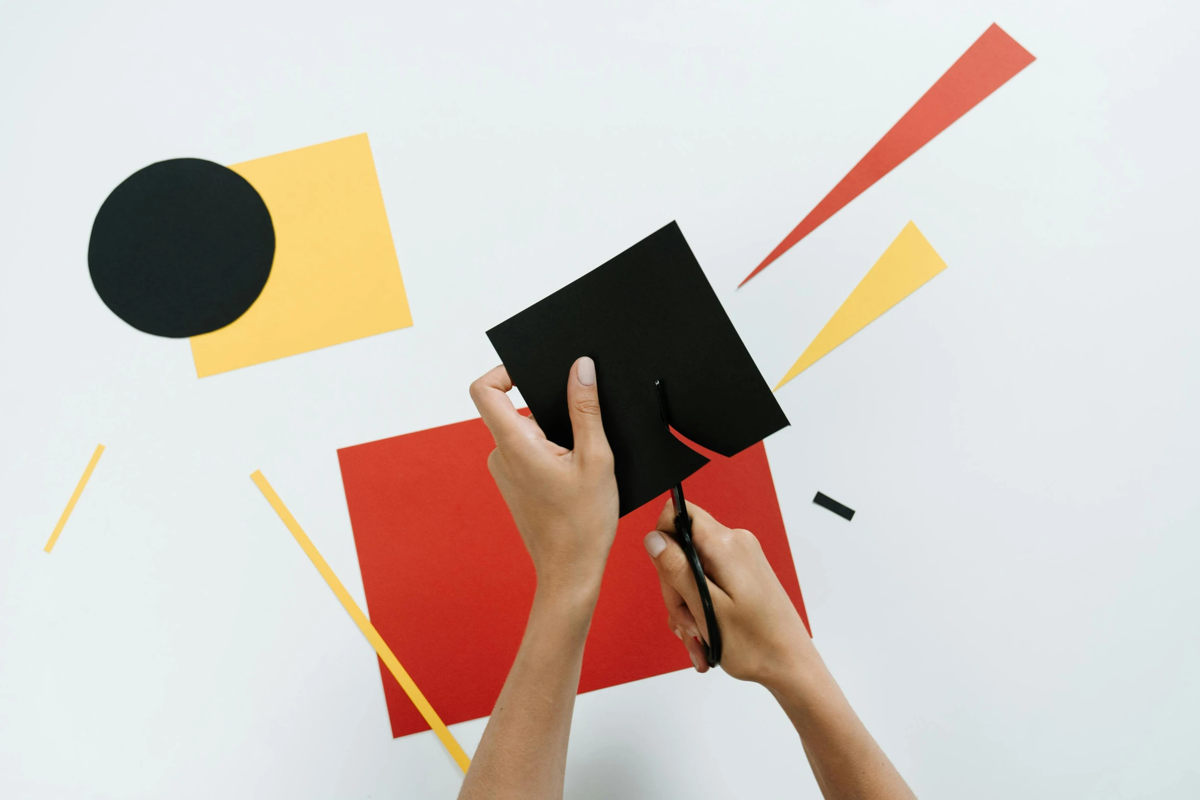 a person cutting a piece of paper with scissors, inspired by El Lissitzky, pexels contest winner, suprematism, yellows and reddish black, square, post graduate, digital matte black paper art