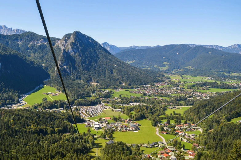 a view of a town from the top of a ski lift, by Sebastian Spreng, pexels contest winner, sunny summer day, avatar image, square, lush forest in valley below