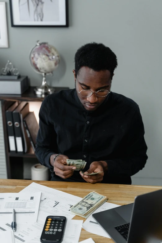 a man sitting at a desk with a laptop and a calculator, by Adam Rex, pexels contest winner, renaissance, afroamerican, made of money, wearing a black shirt, gif