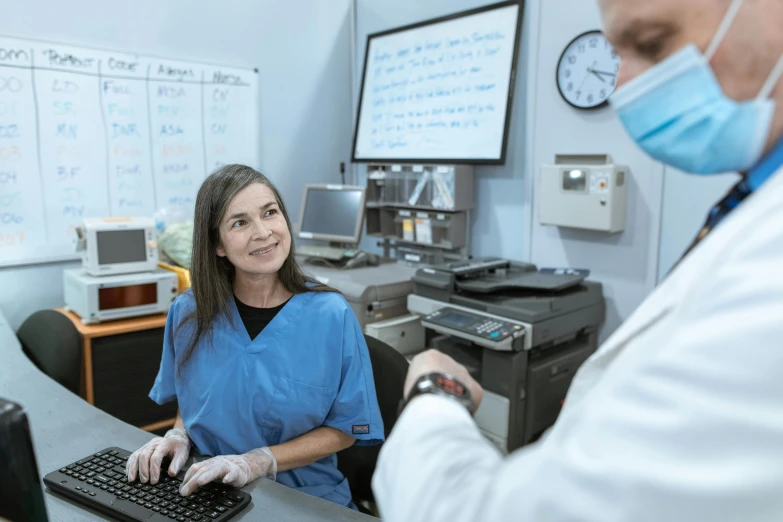 a woman sitting at a desk in front of a computer, surgical supplies, welcoming smile, lachlan bailey, at checkout