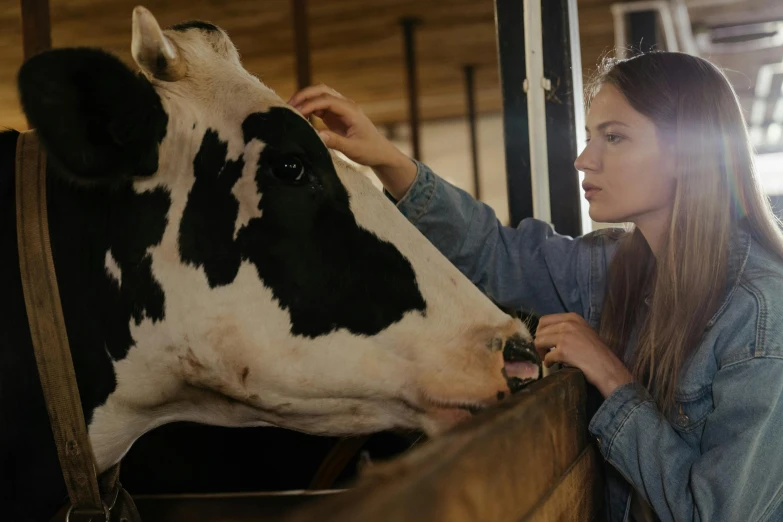 a woman standing next to a black and white cow, trending on pexels, inside a barn, 8 k ultra realistic animal, thumbnail, ad image