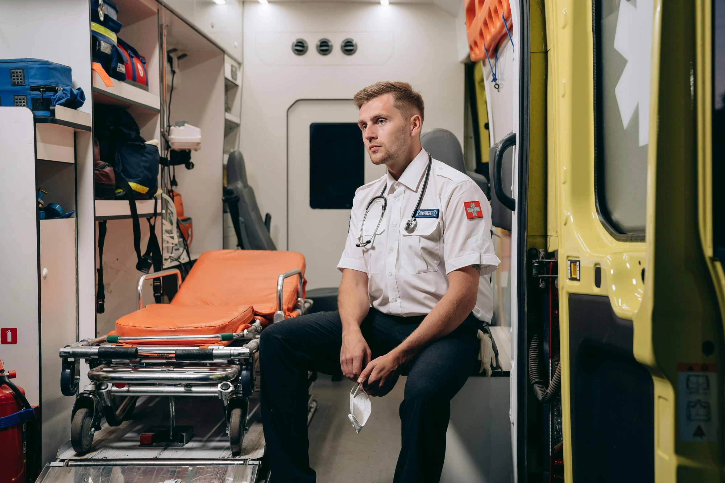 a paramed sits in the back of an ambulance, a portrait, pexels, full body hero, paul barson, canada, jakub gazmercik