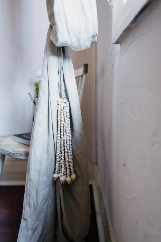 a white chair sitting in a room next to a window, a portrait, inspired by Marià Fortuny, unsplash, short dreadlocks with beads, detail shot, cloth accessories, dwell