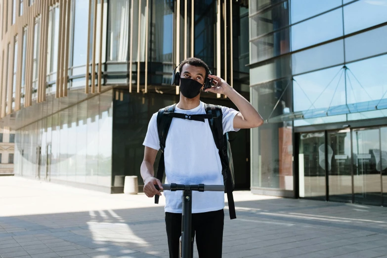 a man on a scooter talking on a cell phone, pexels contest winner, white man with black fabric mask, with a backpack, wearing headset, university