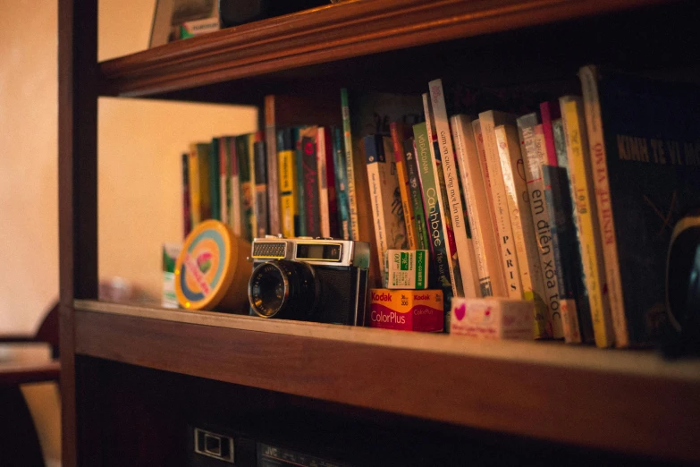 a bookshelf filled with lots of books and a camera, unsplash, private press, toy camera, wooden desks with books, lo - fi, maintenance photo