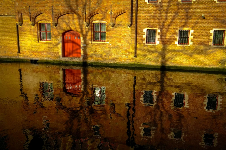 a red fire hydrant sitting in the middle of a body of water, a photo, inspired by Pieter de Hooch, pexels contest winner, trees cast shadows on the wall, 2 0 0 4 photograph, golden windows, water reflecting suns light