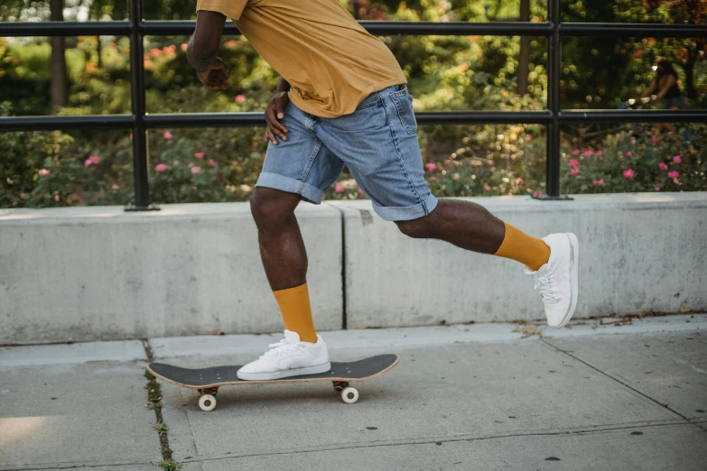a man riding a skateboard down a sidewalk, pexels contest winner, gold soccer shorts, white and yellow scheme, gray shorts and black socks, kano)