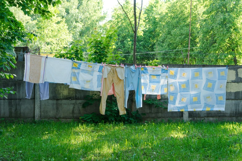 clothes hanging out to dry on a clothes line, inspired by Elsa Bleda, pexels contest winner, process art, patchwork-streak style, ukrainian national clothes, vines hanging from trees, in blue and yellow clothes
