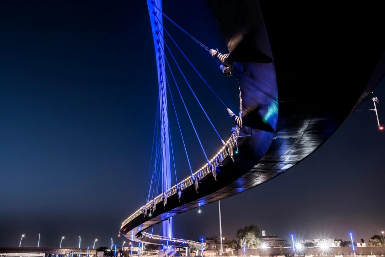 a bridge over a body of water at night, inspired by Zaha Hadid, unsplash contest winner, interactive art, london eye, blue and black, medium closeup shot, award winning masterpiece photo