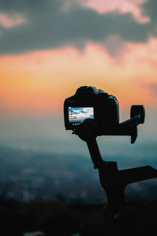 a person taking a picture with a camera, by Robbie Trevino, pexels contest winner, towering over your view, home video footage, at the sunset, on display