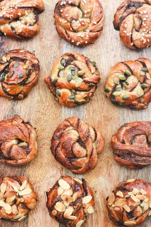 a wooden cutting board topped with lots of pastries, twisting leaves, 6 pack, swedish, woodfired