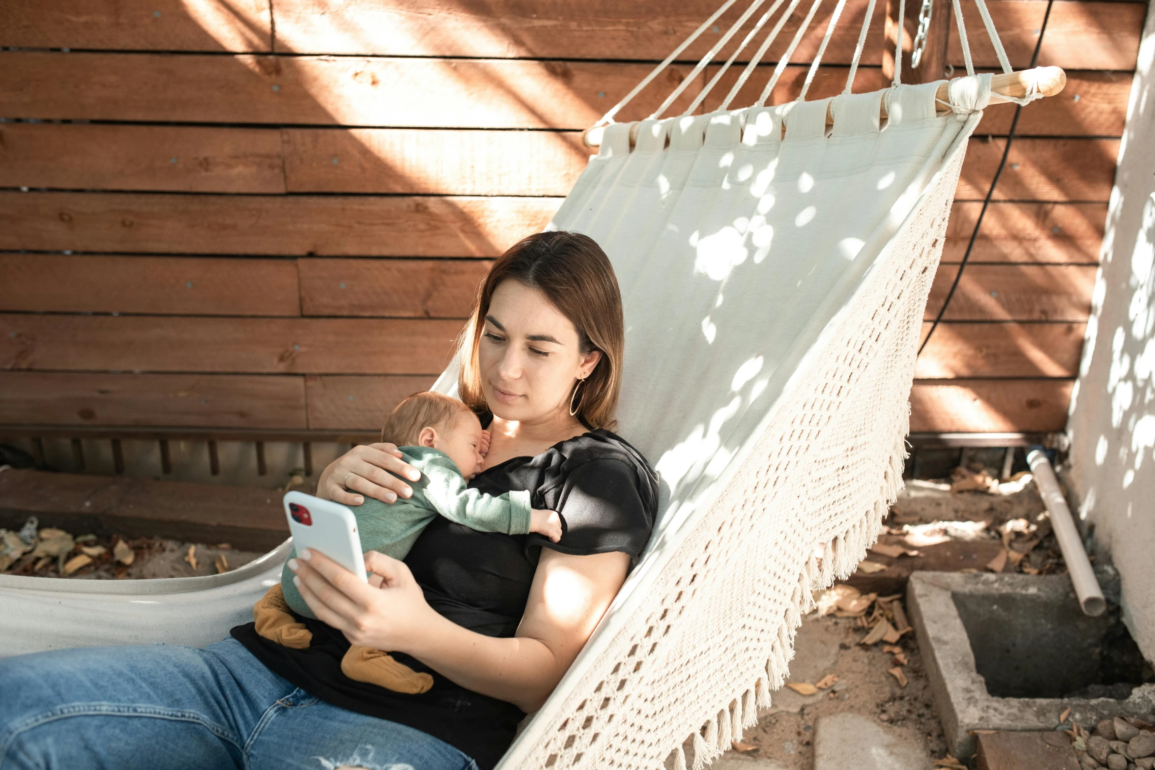 a woman sitting in a hammock reading a book, pexels contest winner, happening, babies in her lap, looking at his phone, avatar image, full frame image