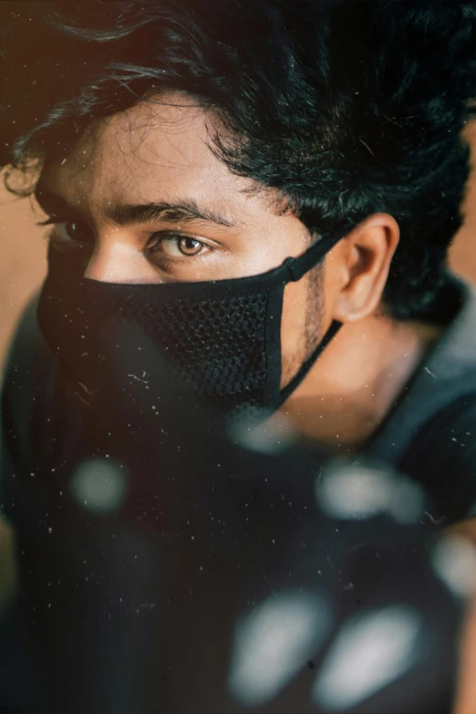 a close up of a person wearing a mask, a picture, trending on pexels, portrait of a rugged young man, vinayak, shady look, indoor picture