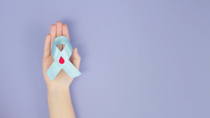 a woman's hand holding a blue ribbon with a red heart, a photo, trending on pexels, antipodeans, made of lab tissue, pastel blue, tumors, paper cut out