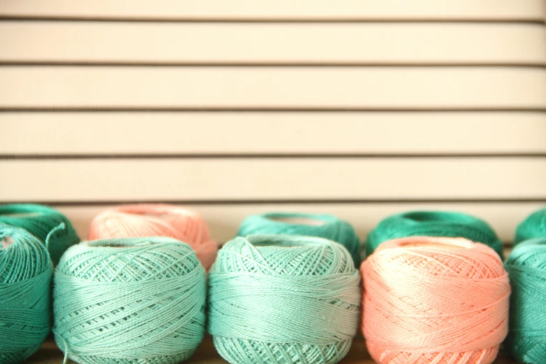 a row of balls of yarn sitting on top of a table, a cross stitch, flickr, minimalism, teal and pink, fine lace, shot on sony alpha dslr-a300, pastel bright colors