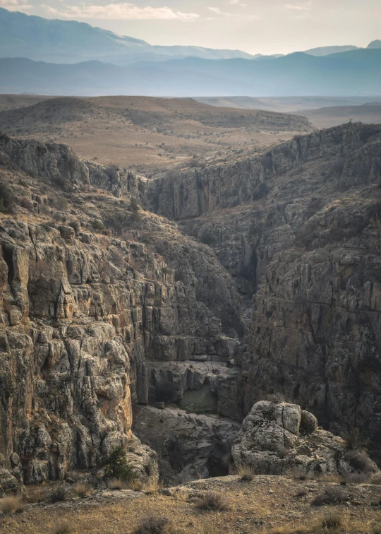 a view of a canyon from the top of a mountain, by Ibrahim Kodra, les nabis, 4k image”, portrait”, grain”, very detailed ”