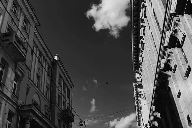 a black and white photo of a city street, a black and white photo, by Emma Andijewska, pexels contest winner, postminimalism, airplane in the sky, lviv, under blue clouds, street of moscow