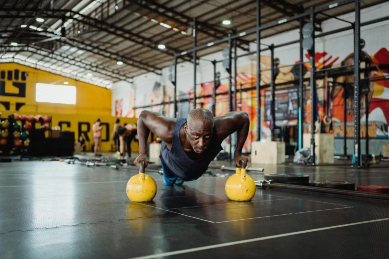 a man doing push ups in a crossfit gym, pexels contest winner, yellow and charcoal, emmanuel shiru, avatar image, bells