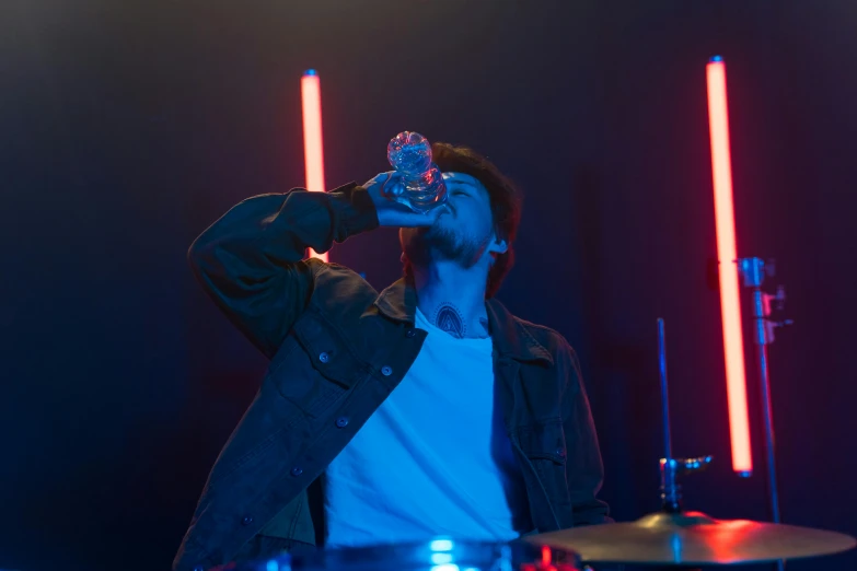 a man that is standing in front of a drum, pexels, drinking a bottle of coca-cola, ( ( stage lights ) ), liam, dynamic scene