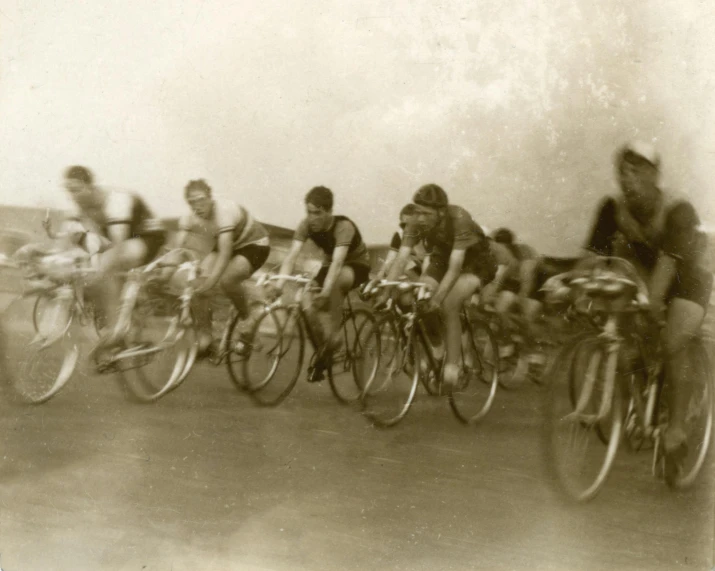 a group of people riding bikes down a street, a black and white photo, by Tony Tuckson, vintage race footage, old school fpr, sepia, promo image