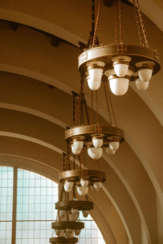 a bunch of lights hanging from the ceiling of a building, by Morris Kestelman, art nouveau, domes, train station, golden arches, gallery lighting