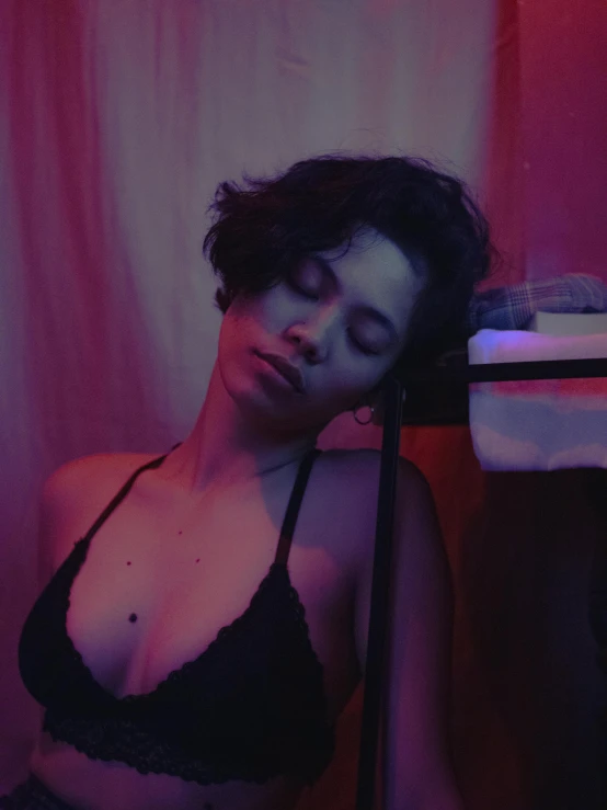 a woman in a black bra top holding a hair dryer, an album cover, trending on unsplash, massurrealism, purple ambient light, her eyes are closed, low quality photo, bella poarch