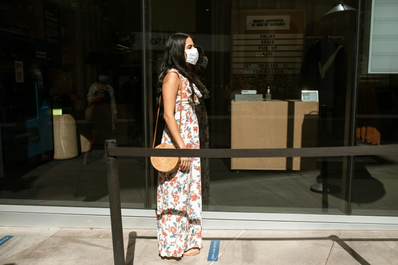 a woman wearing a face mask standing in front of a store, a picture, wearing sundress, bay area, : :, multiple stories