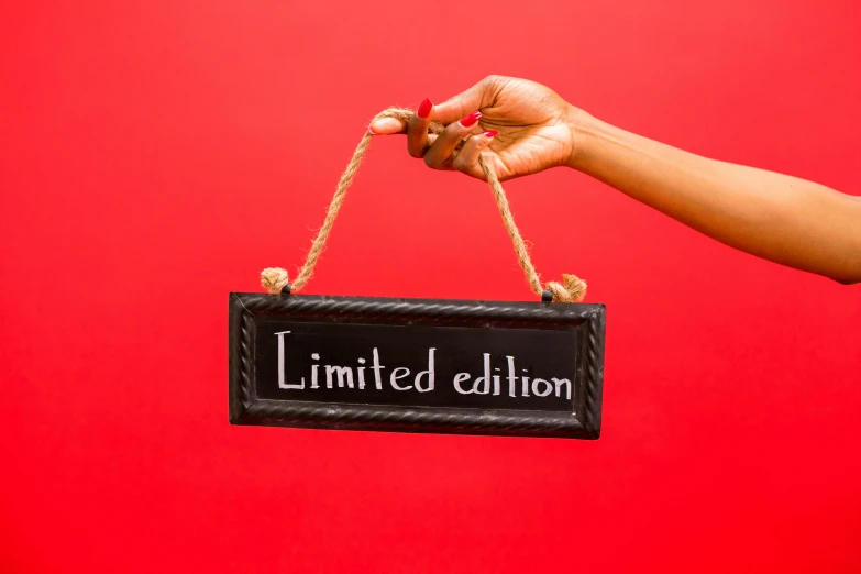 a hand holding a sign that says limited edition, pexels contest winner, happening, in red background, lacquered, handcrafted, taken from the high street